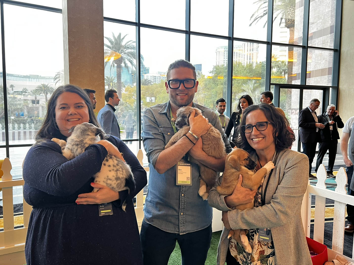 A group of people holding adorable puppies and feeling the benefits of Puppy Love added to their Los Angeles to San Diego company wellness programs.