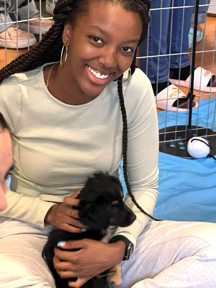A girl holding a black puppy - Puppy Love is the best workplace wellness ideas.