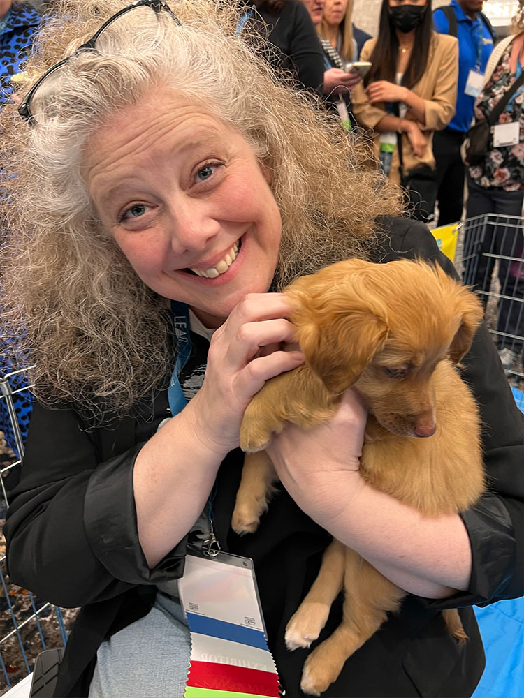A woman holding an adorable puppy at a Puppy Love puppy lounge in Los Angeles to San Diego, CA!